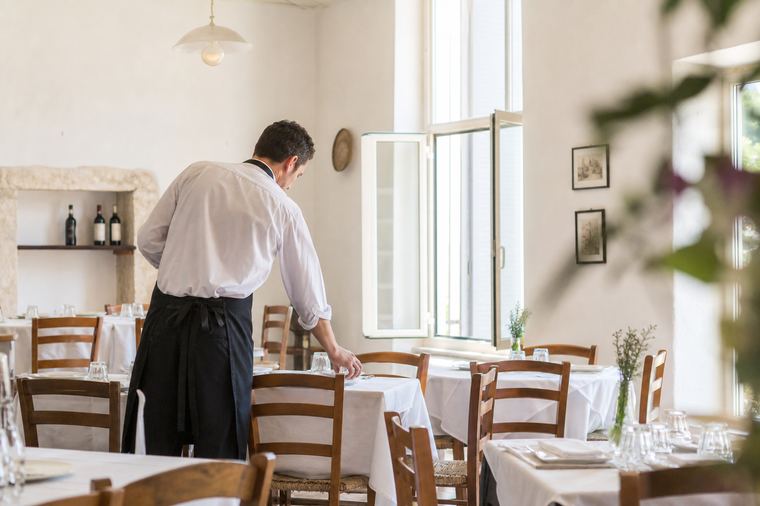 Tavola apparecchiata per la cena con calici da vino, posate e piatti disposti con cura