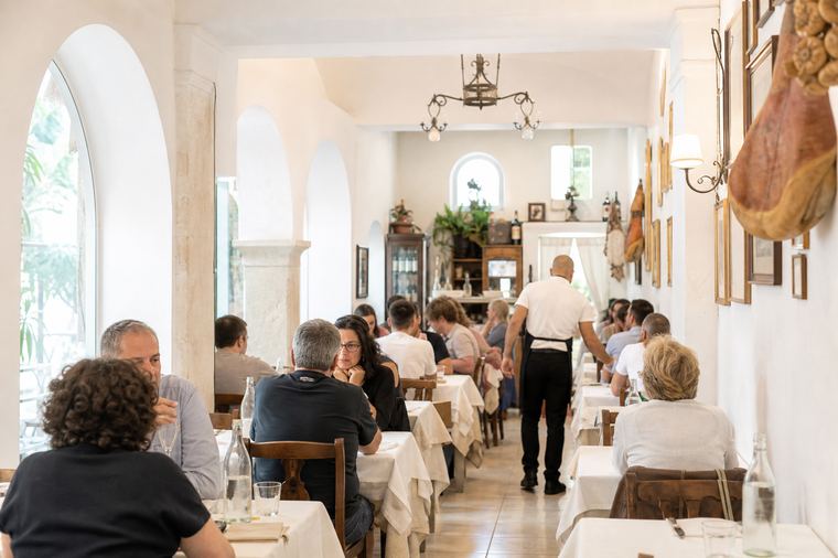 Tavoli e sedie di legno disposti in una sala pronta ad accogliere i commensali