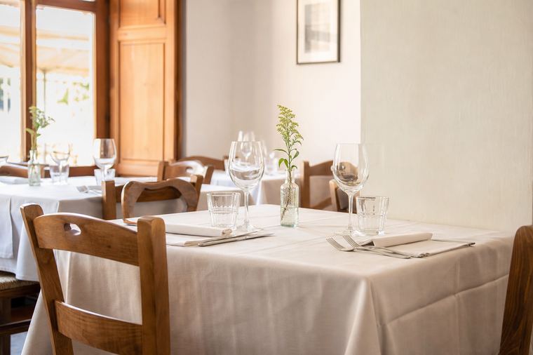 Tavolo con panca accostato alla finestra, apparecchiatura assente e nessun cliente seduto in sala